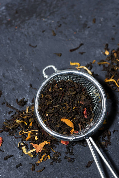 dry black tea with herbs in a strainer, vertical - Foto, afbeelding