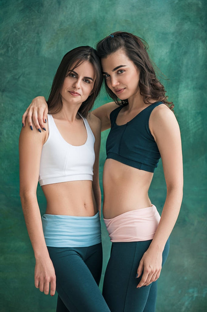 Two young sporty women posing at gym. - 写真・画像