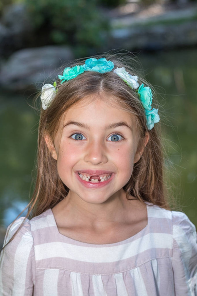Funny portret of little girl who lost front teeth. City park in the summer time - Photo, Image