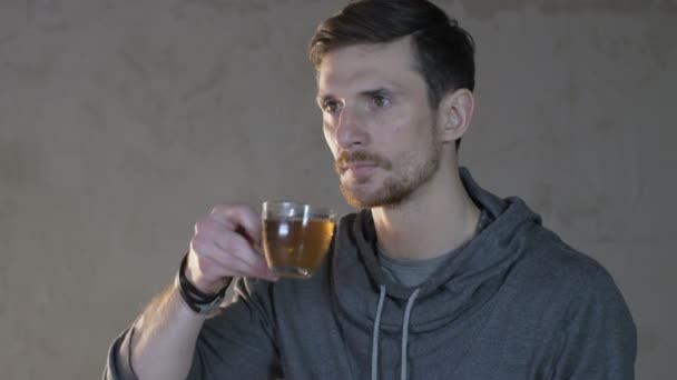 Młody mężczyzna napoje herbata ze szkła - Materiał filmowy, wideo