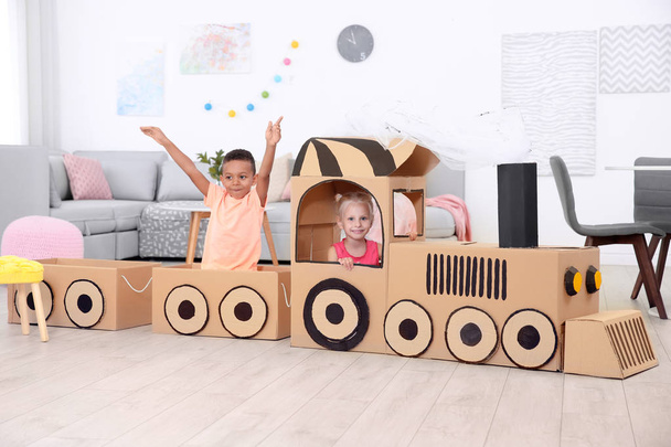 Cute children playing with cardboard train at home - Fotó, kép