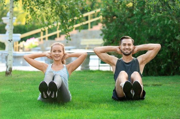 Young man and woman doing exercises in park - Photo, image