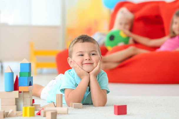 Милий хлопчик грає з блоками в приміщенні
 - Фото, зображення