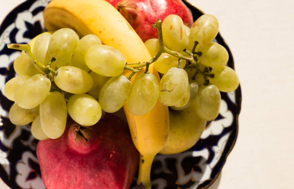 Set of fresh fruits placed on ornamental ceramic plate. - Photo, image
