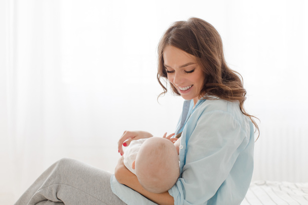 Cheerful woman with baby breast feeding - Fotoğraf, Görsel