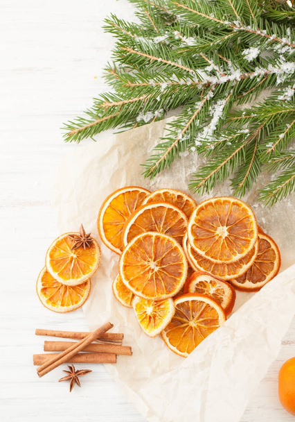 Dried oranges, cinnamon sticks with snow-covered fir branch - Foto, immagini