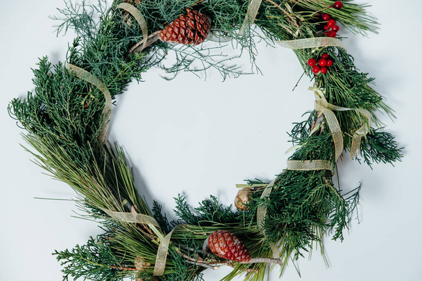 Рождественский венок с еловыми конусами на белом фоне. Вид сверху
 - Фото, изображение
