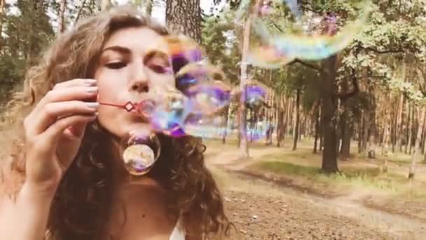 Beautiful young woman blows soap bubbles - Footage, Video