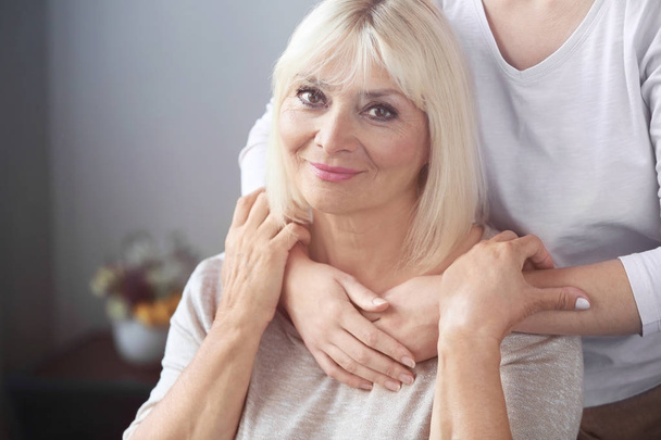 Mature and young women hugging indoors. Elderly care concept - Photo, Image