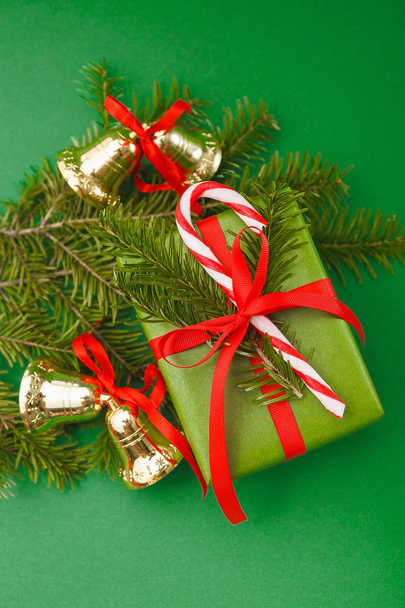 Christmas decorations and holiday wrapped gift box on green background, top view - Photo, Image