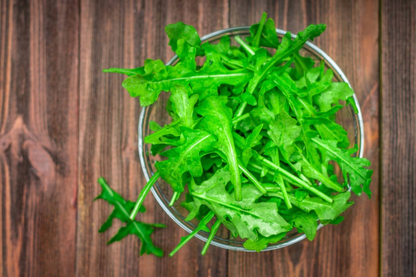 Fresh juicy leaves of arugula on a brown wooden table. - Photo, Image
