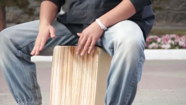 Een straat drummer muzikant speelt een percussie-instrument Cajon. - Video