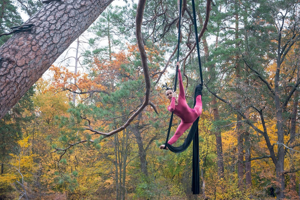 Mulher dançando com seda aérea em um fundo de árvores
.  - Foto, Imagem