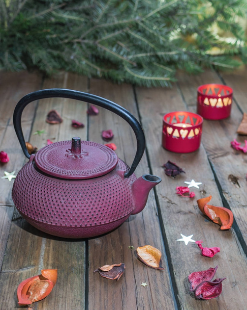 Red cast-iron Chinese teapot on a background of Christmas candle - Foto, Bild