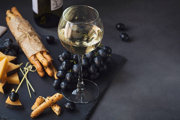 Cheese plate served with crackers, grapes and glass of white win - Foto, Bild