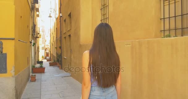 Nuori turistinainen kävelee pienellä kadulla aurinkoisena päivänä. Tyttö viettää lomaa Euroopassa, tutkia keskiaikainen vanhakaupunki
. - Materiaali, video