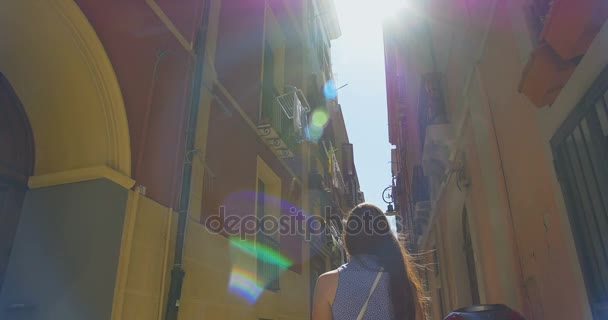 晴れた日の小さな通りを歩く若い観光客女性。中世の旧市街を探索、ヨーロッパで休暇を過ごす女の子. - 映像、動画