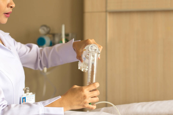 Медсестра дает пациенту воду, используя стеклянный шприц для орошения носа.
 - Фото, изображение