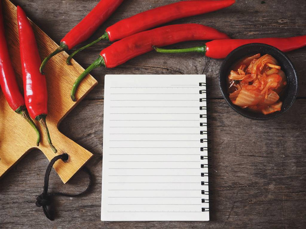 Kimchi korean food with blank notepad and chilli peppers on wooden background - Foto, Imagen