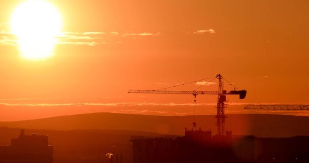 Věžový jeřáb na pozadí zapadajícího slunce. Podsvícení. Jekatěrinburg, Rusko  - Fotografie, Obrázek
