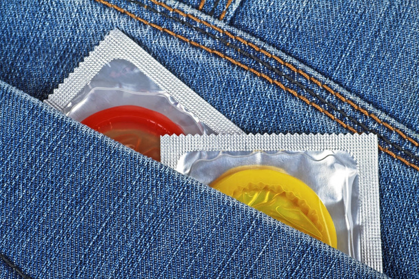Two colored condoms in a pocket of jeans - Valokuva, kuva