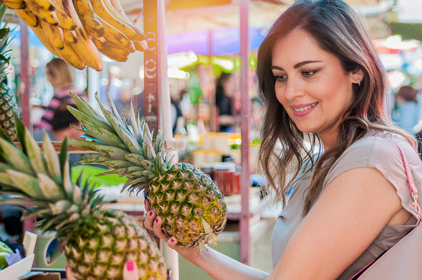 Attractive woman choosing pineapple - 写真・画像