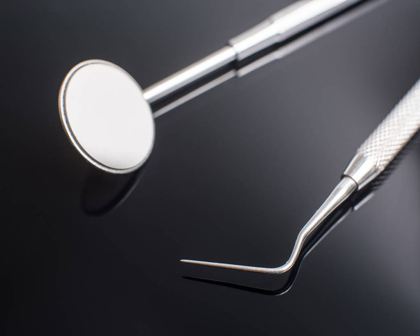 Close-up professional dental tools - dental mirror and dental probe. Image isolated on black background - Foto, Bild