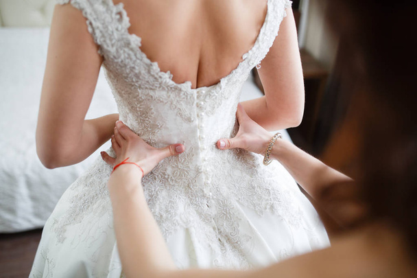Bridesmaid is helping the bride to dress - Foto, Imagen
