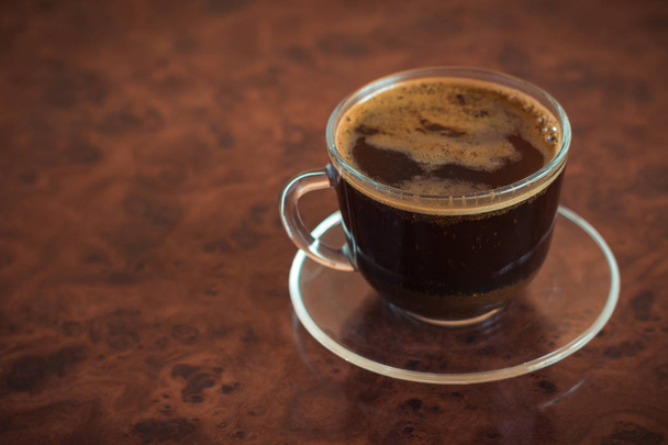 eine Tasse frisch gebrühten Kaffee auf einem braunen Tisch. - Foto, Bild