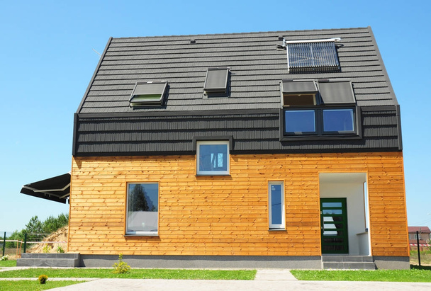 Moderni talo, jossa energiansäästö ja energiatehokkuus. Eco-house tai puinen eko-home ullakko kattoikkunat, eristys, aurinkopaneelit ja aurinko vedenlämmitin (SWH) järjestelmä
.  - Valokuva, kuva