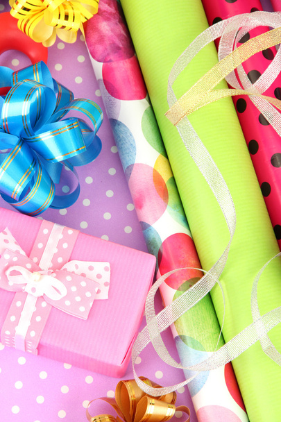 Rolls of Christmas wrapping paper with ribbons, bows on color background - 写真・画像