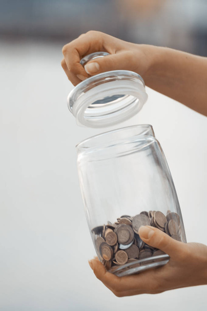 投資、退職金、税金、受動的所得概念の垂直方向のビュー。ガラスのコイン手に jar、焦点をぼかし - 写真・画像