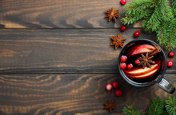 Weihnachtsglühwein mit Apfel und Preiselbeeren. Urlaubskonzept mit Tannenzweigen, Preiselbeeren und Gewürzen. - Foto, Bild