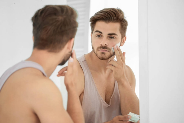Young man applying facial cream  - 写真・画像
