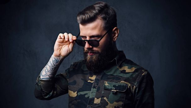 Portrait of bearded tattooed hipster male dressed in a military - Photo, Image