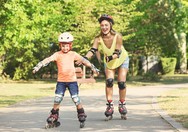 Mother with son on roller skates in summer park - Фото, изображение
