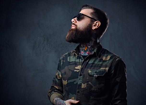 Retrato de un hombre hipster tatuado barbudo vestido de militar
 - Foto, imagen