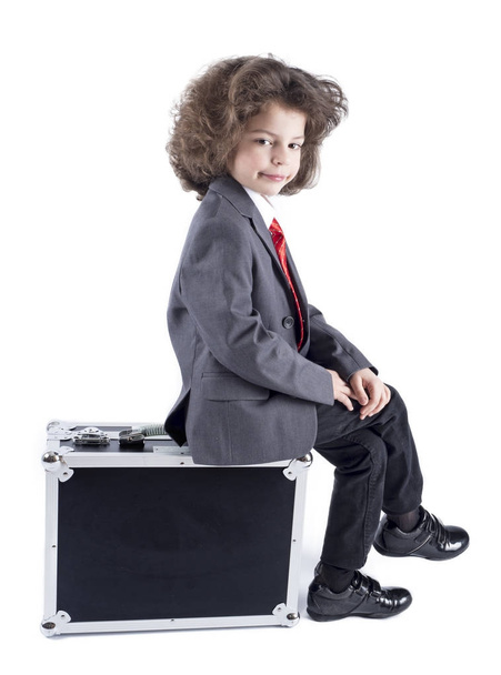 Little boy sitting on suitcase, preparing for the holiday. Business boy, cheerful active child. Travel.  White background - Foto, Imagem