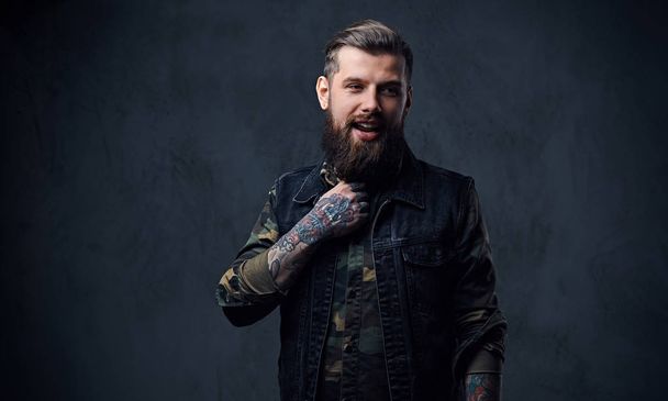 Портрет бородатого татуированного хипстера мужского пола, одетого в военное
 - Фото, изображение