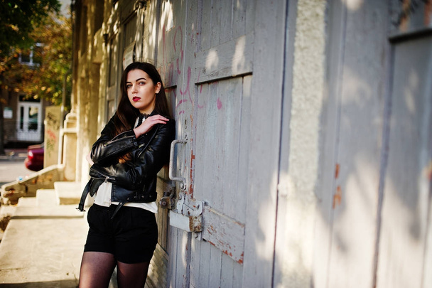 Stylish brunette girl wear on leather jacket and shorts posing a - Foto, afbeelding
