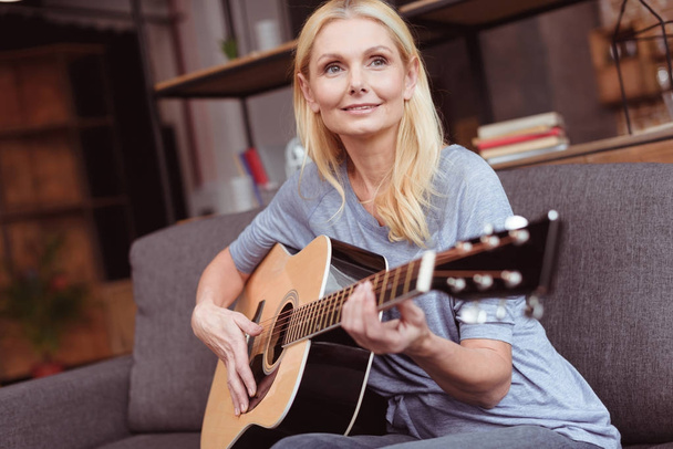 middle aged woman with guitar at home - Foto, imagen