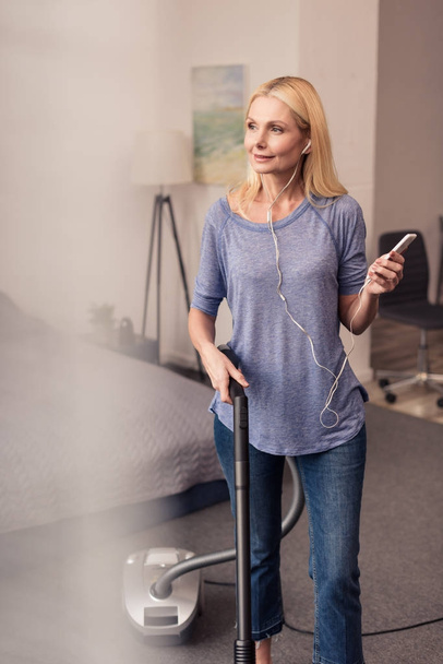 woman using smartphone and vacuum cleaner - Fotoğraf, Görsel