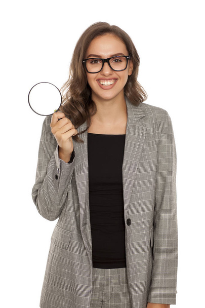 Happy young woman holding a magnifying glass - Fotó, kép