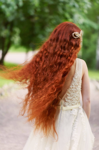 Beautiful red-haired girl with long curly hair in the bride, in a long lace dress.A natural beauty. - Foto, immagini