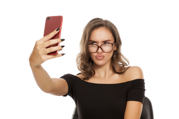 Giovane donna con occhiali fare selfie su uno sfondo bianco
 - Foto, immagini