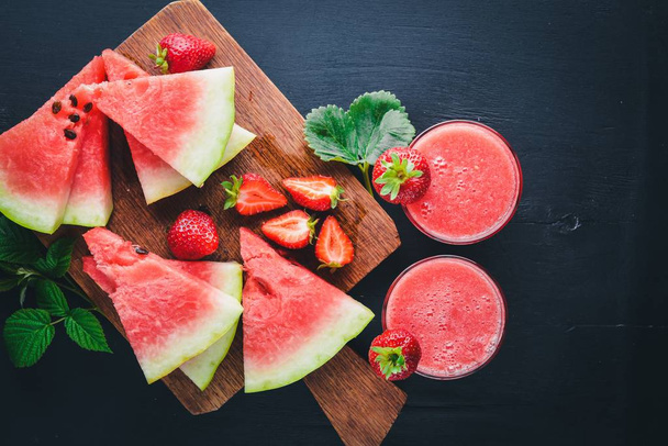 Fresh cocktail of watermelon and strawberries. Mint, ice. On a wooden board. Top view. Free space for your text. - Photo, Image