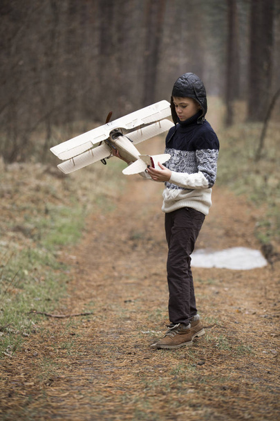a boy plays in the woods with a toy plane. autumn games in the w - Fotó, kép