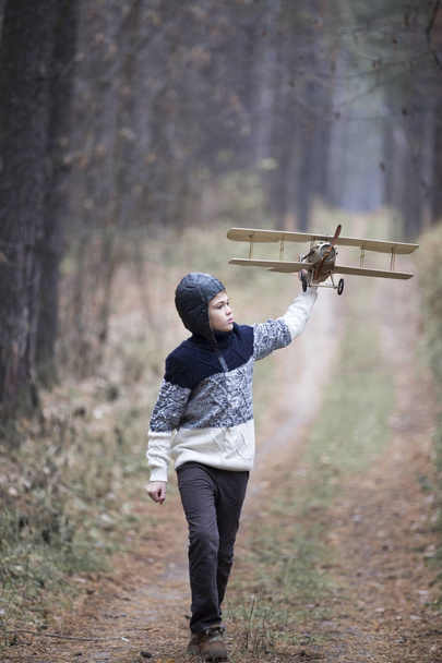 un niño juega en el bosque con un avión de juguete. juegos de otoño en la w
 - Foto, Imagen