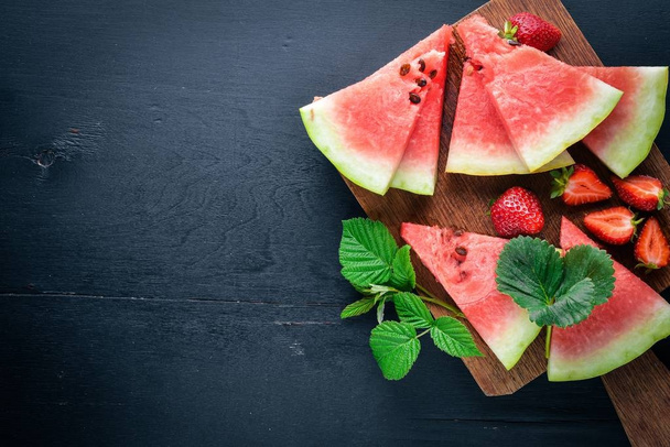 Watermelon, strawberries, mint. On a wooden board. Fruit Slicing. Top view. Free space for your text. - Photo, Image
