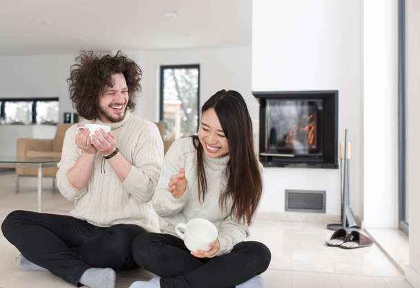 happy multiethnic couple  in front of fireplace - Foto, afbeelding